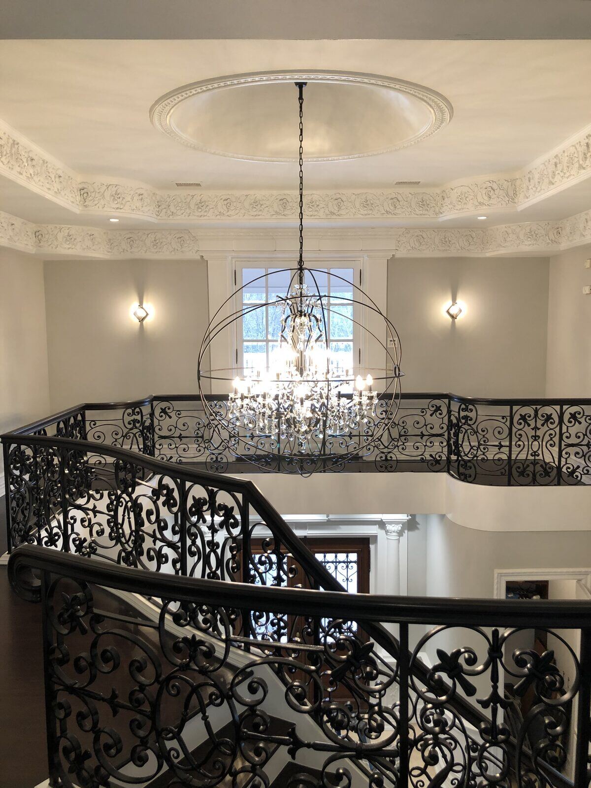 Grand foyer chandelier and staircase sconce lighting installed by Pride Energy