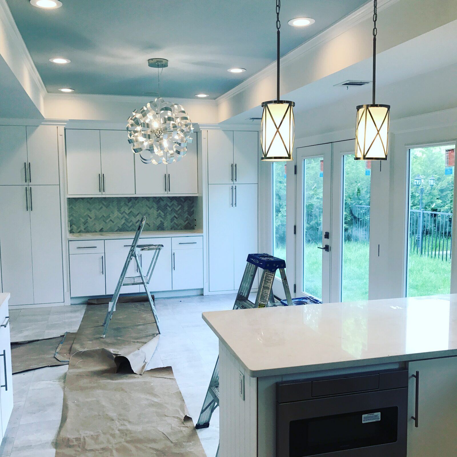 Kitchen recessed lighting, pendant lights, and chandelier mid-installation by Pride Energy